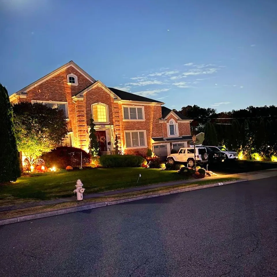 Brick colonial at dusk with warm uplights on the facade
