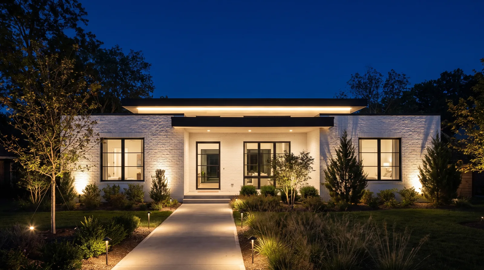 Modern white brick house with black accents, fully lit at night